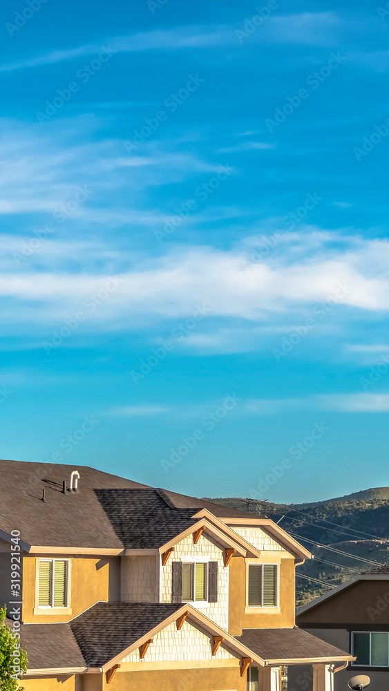 Vertical Houses with view of the roofs and upper storey against hills and vibrant sky Vertical Houses with view of the roofs and upper storey against hills and vibrant sky