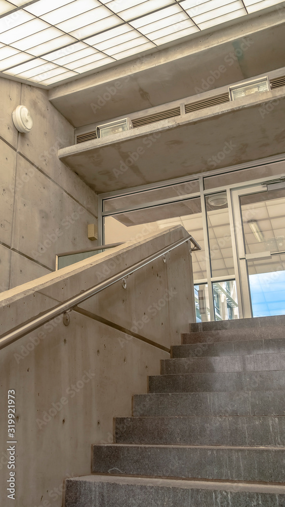 Fototapeta premium Vertical Concrete stairs with side walls and handrails under sloping slant glass roof