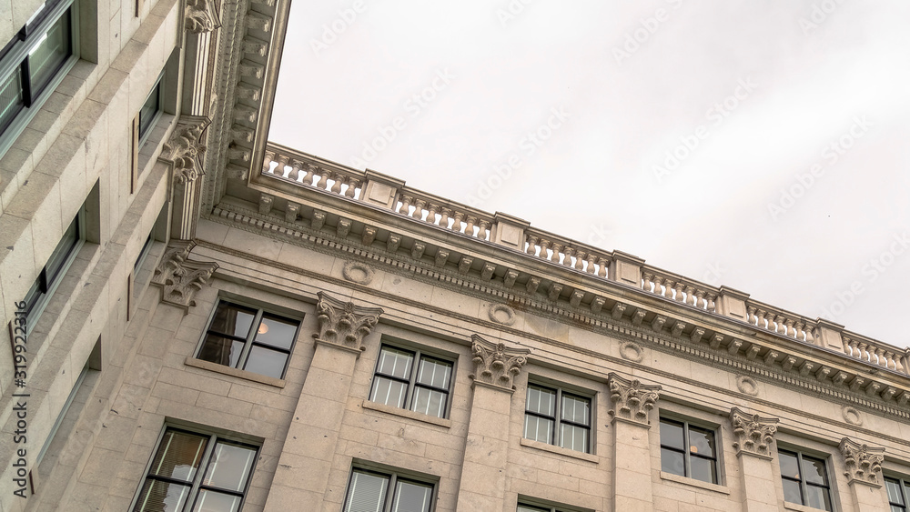 Panorama Building with decorative wall mouldings and shiny windows against cloudy sky Panorama Building with decorative wall mouldings and shiny windows against cloudy sky