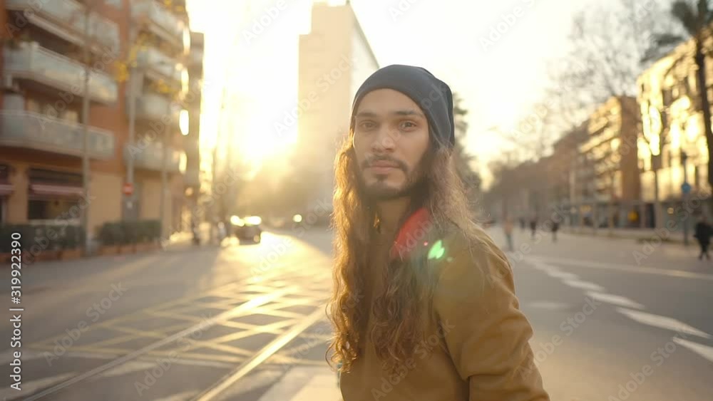 Portrait of long haired hipster walking on street in modern city in slow motion. Stylish man with sunset light Portrait of long haired hipster walking on street in modern city in slow motion. Stylish man with sunset light