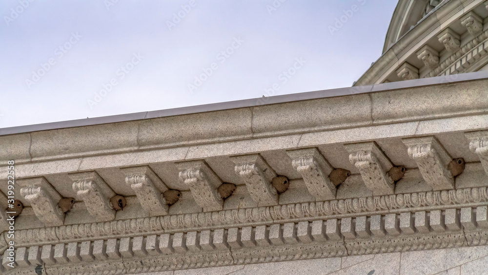 Fototapeta premium Panorama Beehives on the exterior stone wall with decorative mouldings of a building