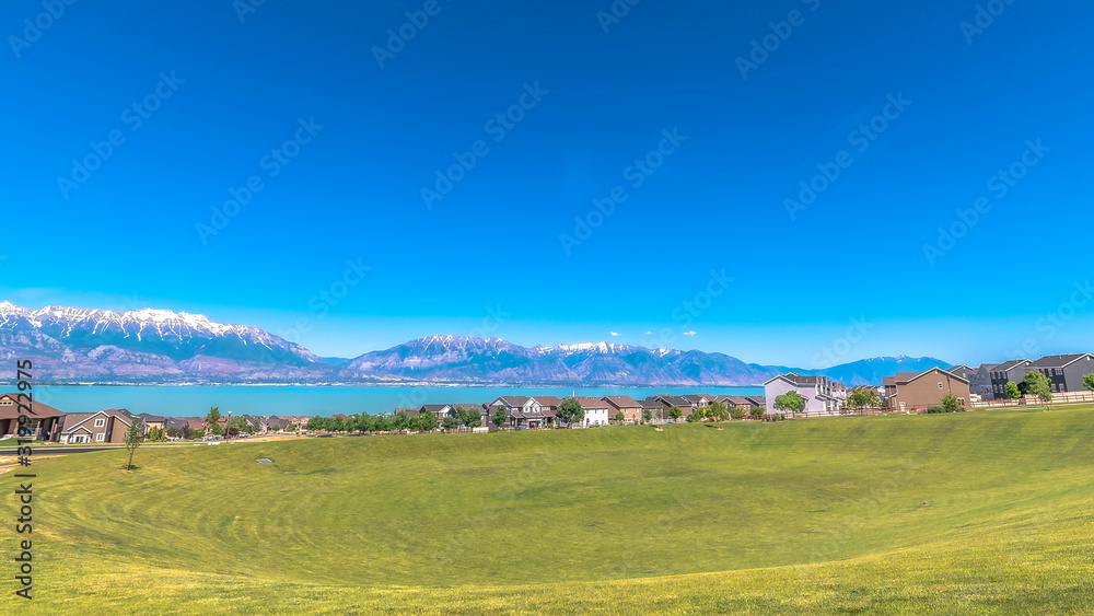 Panorama Scenic view of lake mountain homes and sky with golf course in the foreground