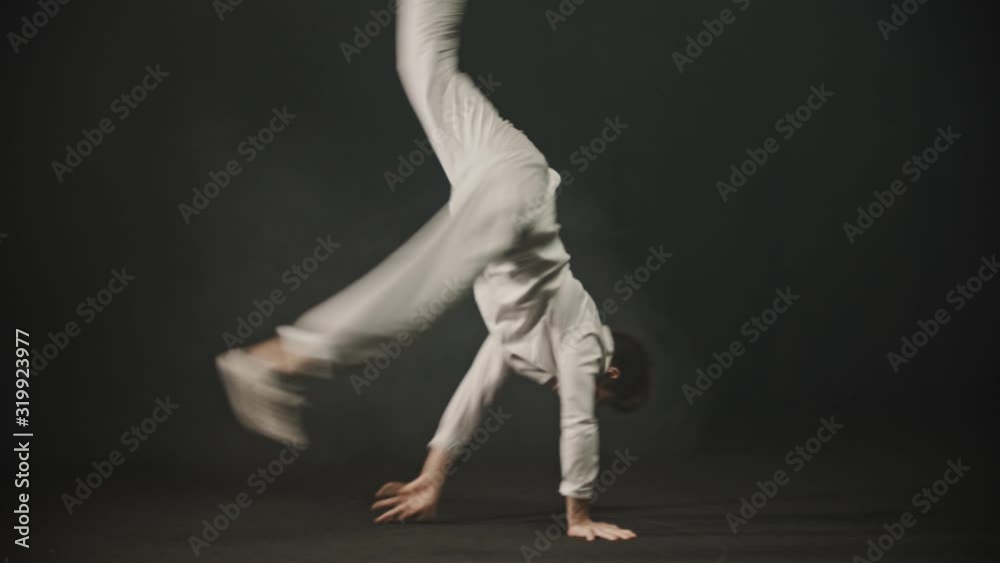 Young man dancer showing breakdance tricks in the dark studio Young man dancer showing breakdance tricks in the dark studio