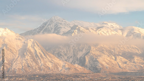 Panorama frame Mount Timpanogos hills and houses blanketed with snow on a cold winter day
