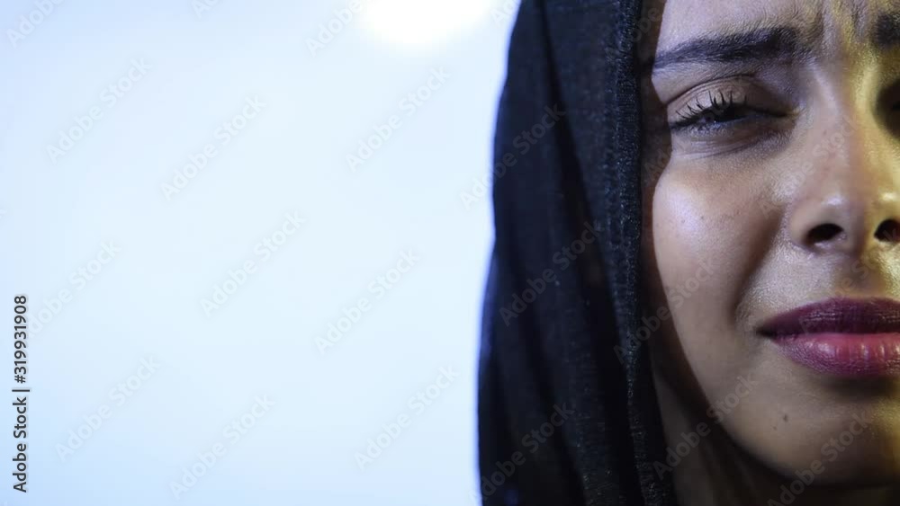 Close portrait of young Muslim woman's face looking at camera in hijab Close portrait of young Muslim woman's face looking at camera in hijab