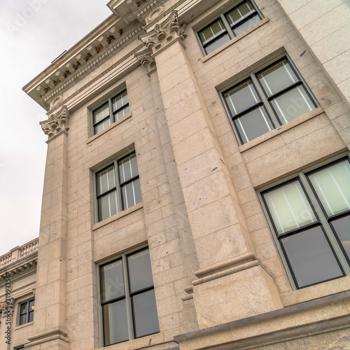 Square Utah State Capitol Building with decorative mouldings viewed against cloudy sky