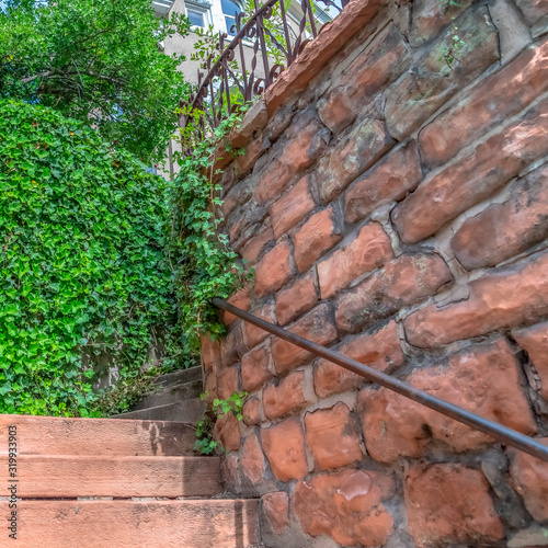 Square frame Close up of outdoor stairs amid stone brick retaining walls that leads to a home
