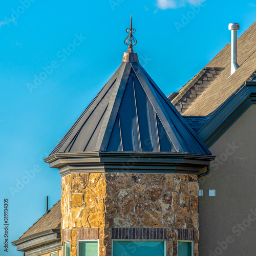 Square Exterior of home with bay window under gray hip roof against blue sky photo