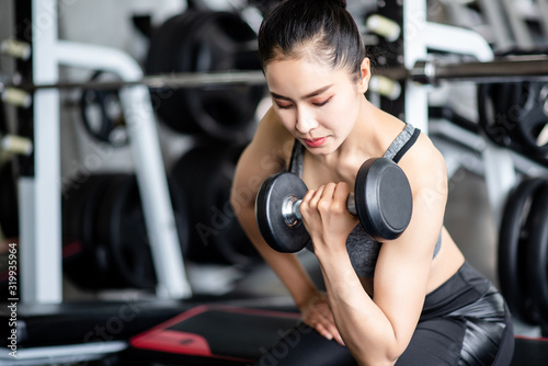 Young healthy woman lifting dumbbells in the gym