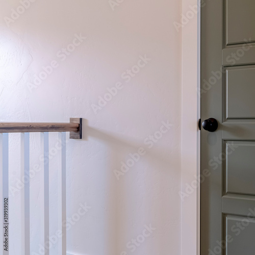 Square frame White railing and gray door against white wall of home with wooden floor