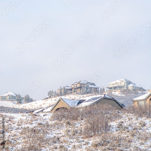 Square Snow covered hill top with snowy houses against vast cloudy sky in winter
