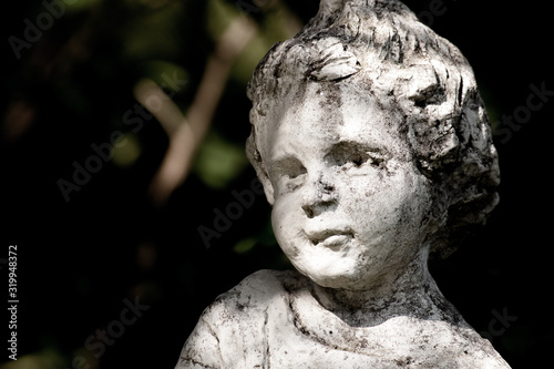 Cloes up photo of arden stone sculpture of a childern. Children statue.