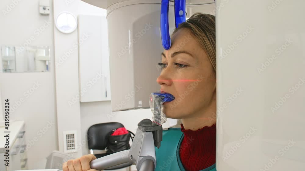 Doctor to take a image 3d scanner tomography of teeth and jaw in modern laboratory dental clinic. Female nurse shows the patient woman an x-ray machine 3d digital scanner. Computer dental diagnostics. Doctor to take a image 3d scanner tomography of teeth and jaw in modern laboratory dental clinic. Female nurse shows the patient woman an x-ray machine 3d digital scanner. Computer dental diagnostics.