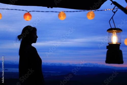 Платно A clean woman's profile silhouette with a sweet lantern and ball lights against the background of fantastic colorful gradation sky