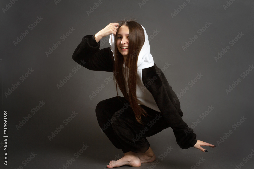 portrait of a brunette girl in the Studio on a plain black background in black and white pajamas with a hood portrait of a brunette girl in the Studio on a plain black background in black and white pajamas with a hood