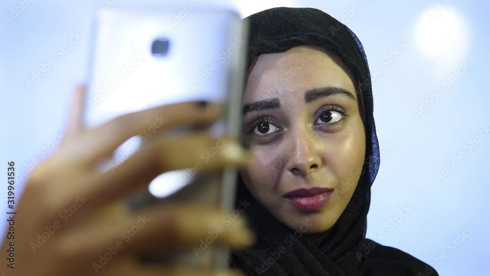 Muslim girl wearing Hijab , using mobile and takes selfies Muslim girl wearing Hijab , using mobile and takes selfies