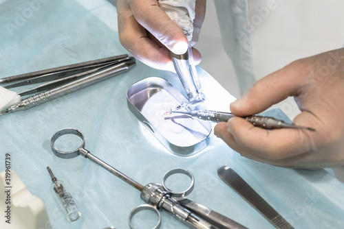 Close-up of the hands of a dentist surgeon on implantation, with dental instrument and surgical template