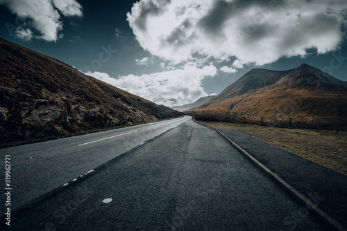 Empty road on a cloudy day through the Scottish highlands and mountains