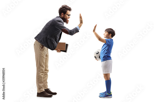 Boy in a jersey with a soccer ball gesturing high five with a male teacher