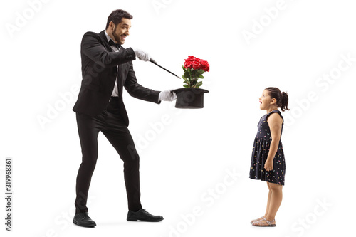 Фотография Magician making flowers appear from a hat and a surprised little girl watching