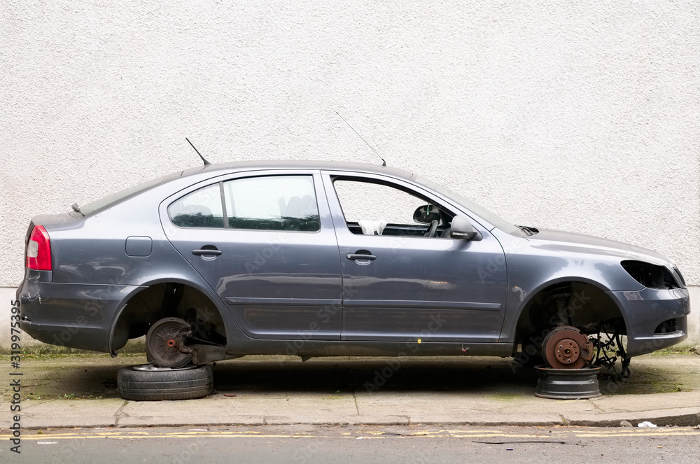 Car with stolen wheels for repair at garage lifted jacked up on bricks