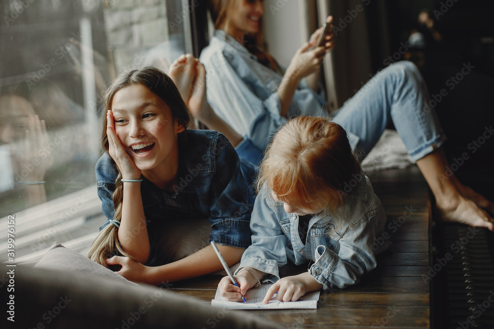 Beautiful mother with two daughters. Family sitting in the room near window Beautiful mother with two daughters. Family sitting in the room near window