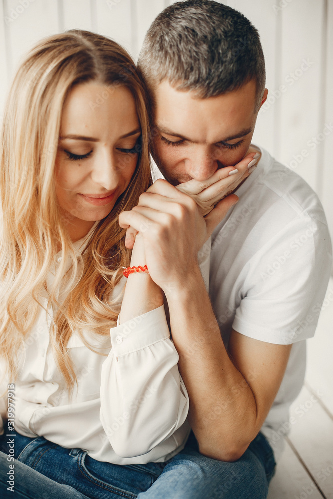 Couple sitting at home. Beautiful blonde with her husband. Man in a white shirt Couple sitting at home. Beautiful blonde with her husband. Man in a white shirt