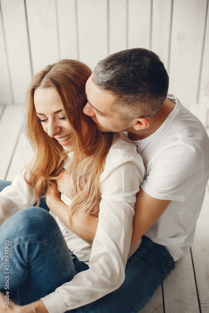Couple sitting at home. Beautiful blonde with her husband. Man in a white shirt Couple sitting at home. Beautiful blonde with her husband. Man in a white shirt