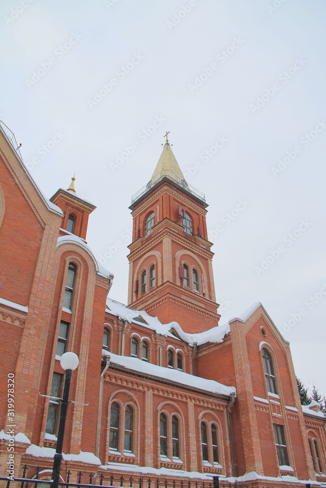 Fragment of a red brick church with windows and gilded roof