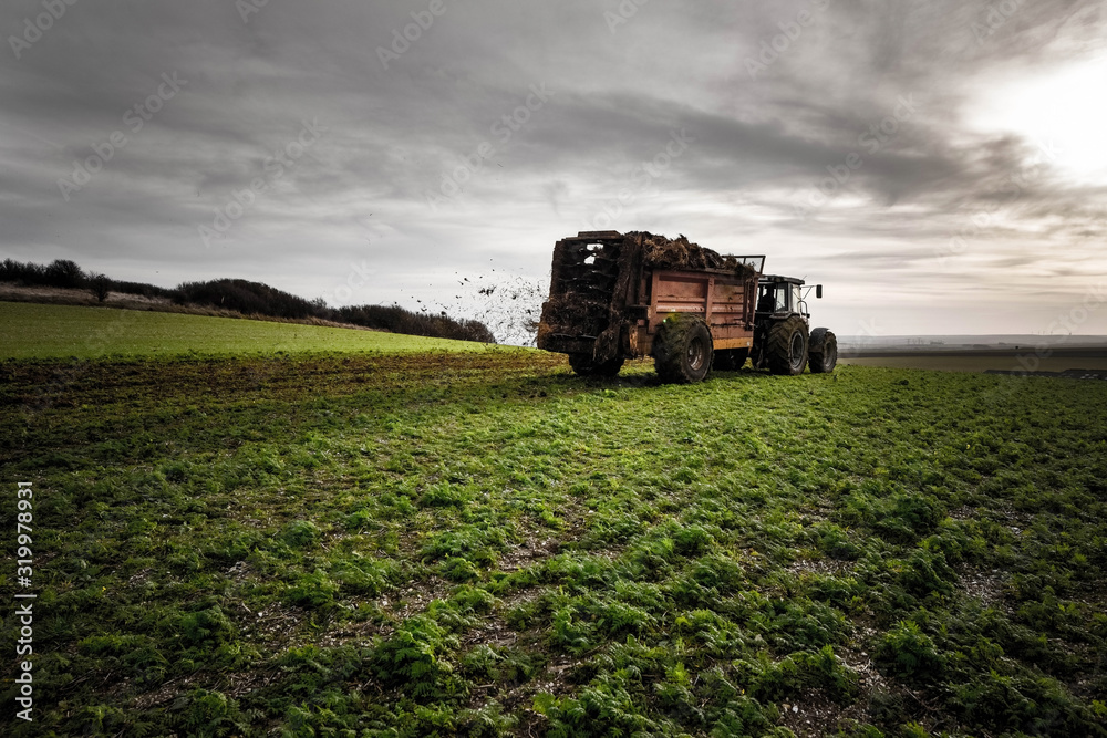 Obraz premium tractor and trailer for spreading manure in fields close up