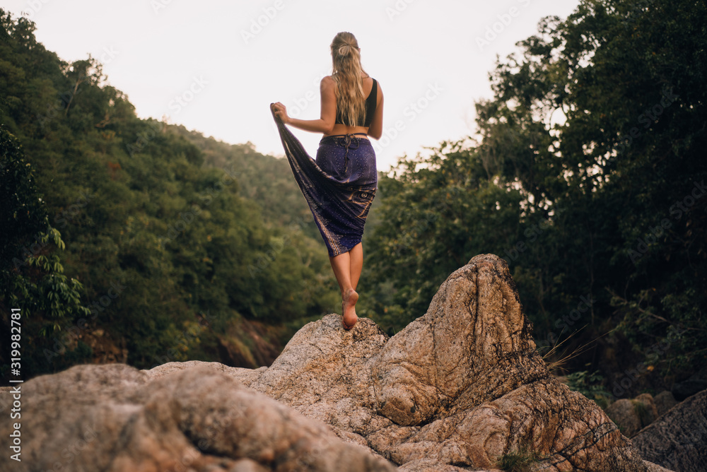 Blonde woman standing on rocks in jungle Blonde woman standing on rocks in jungle