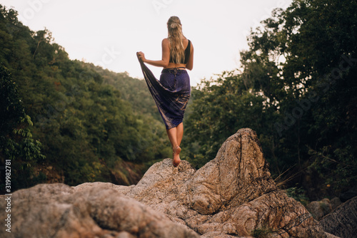 Blonde woman standing on rocks in jungle