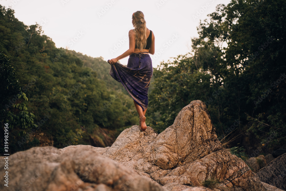 Blonde woman standing on rocks in jungle