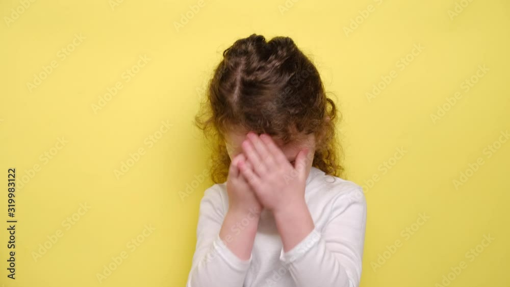 Upset little girl blows cheeks in dissatisfaction, expresses negative emotions and feelings, feels abused and offended stands over yellow background. Unhappy child frowns face, shows antipathy Upset little girl blows cheeks in dissatisfaction, expresses negative emotions and feelings, feels abused and offended stands over yellow background. Unhappy child frowns face, shows antipathy