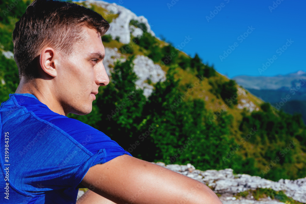 Fit male fitness trainer chilling on top of a mountain on a sunny day. Fit male fitness trainer chilling on top of a mountain on a sunny day.