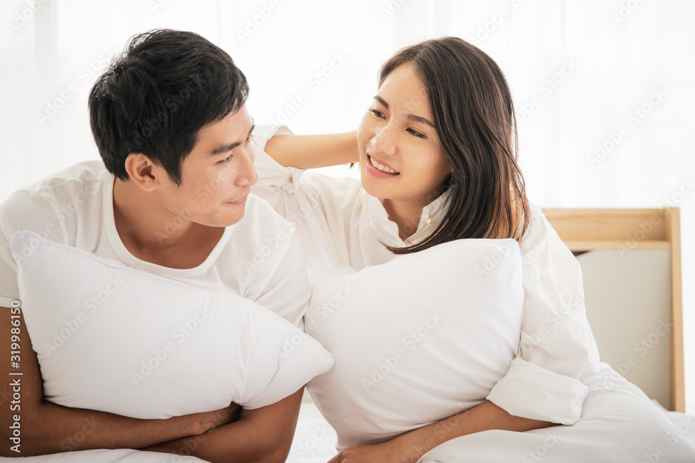 Funny and romantic Asian couple's portrait in bedroom with natural light from window. Romantic couple in Valentine's day concept. Funny and romantic Asian couple's portrait in bedroom with natural light from window. Romantic couple in Valentine's day concept.