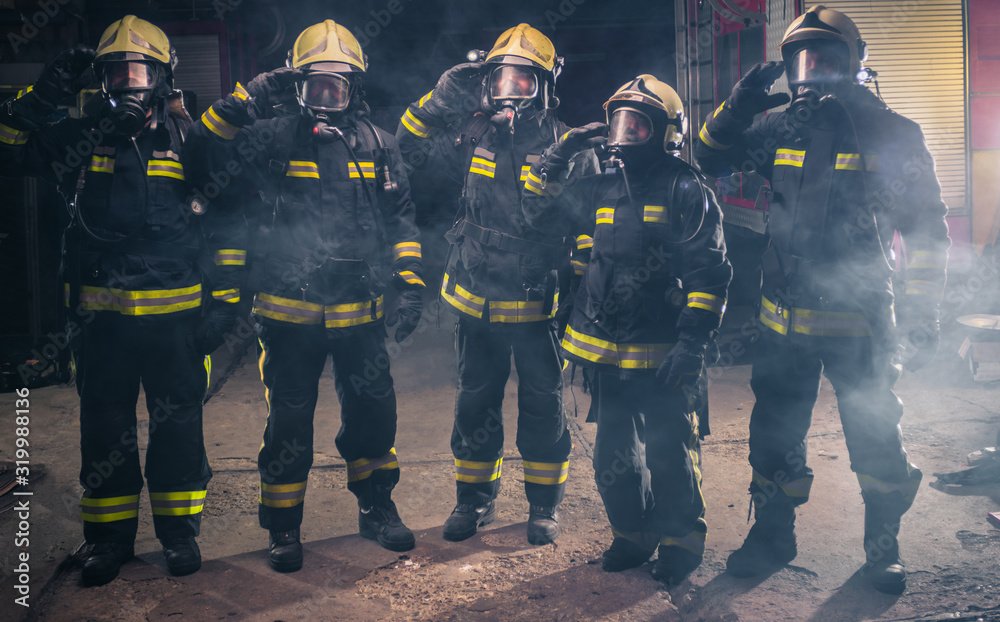 Team of fireman standing the middle of the fire extinguisher's smoke inside the fire department Team of fireman standing the middle of the fire extinguisher's smoke inside the fire department