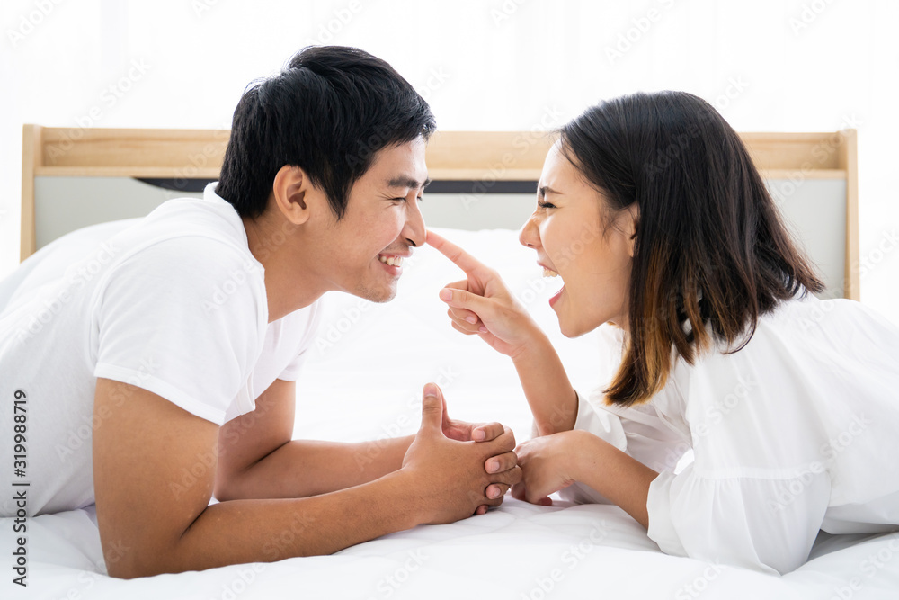 Funny and romantic Asian couple' portrait in bedroom with natural light from window, concept of relationship between husband and wife and being a family. Funny and romantic Asian couple' portrait in bedroom with natural light from window, concept of relationship between husband and wife and being a family.