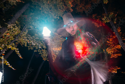 Wizard (mage) casting a spell with his magical staff while standing in an enchanted forest..