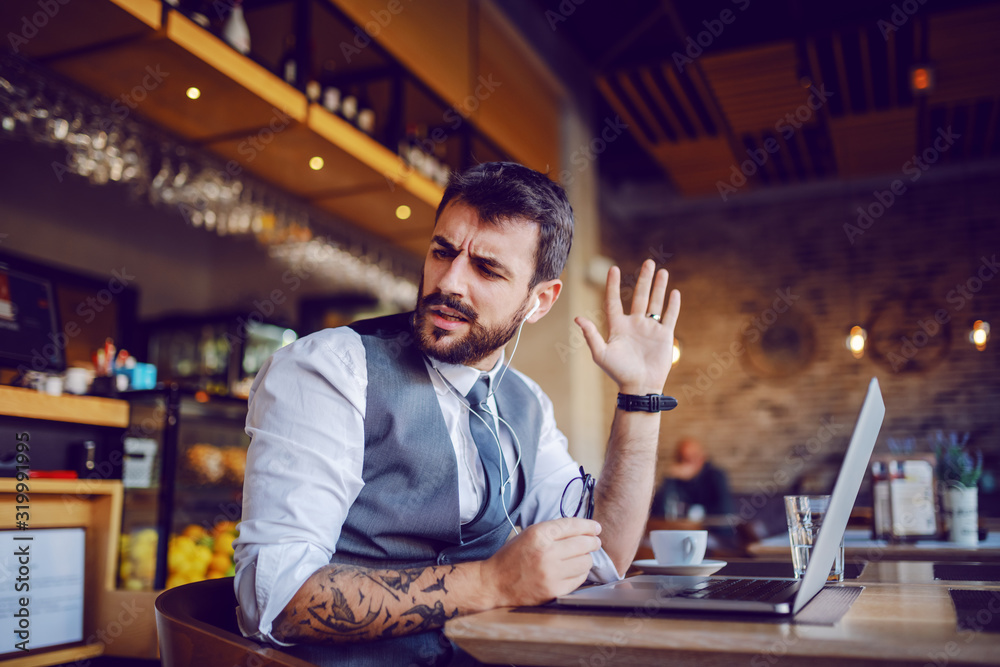 Fototapeta premium Annoyed caucasian good-looking bearded businessman in suit having argument with employee over laptop.