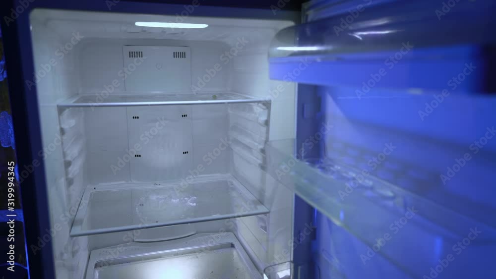 Opening and closing the door of an empty fridge. Nothing to eat or strict dieting. Night hunger. Hangover. Bachelor's fridge, view from behind. Dirty fridge. Opening and closing the door of an empty fridge. Nothing to eat or strict dieting. Night hunger. Hangover. Bachelor's fridge, view from behind. Dirty fridge.
