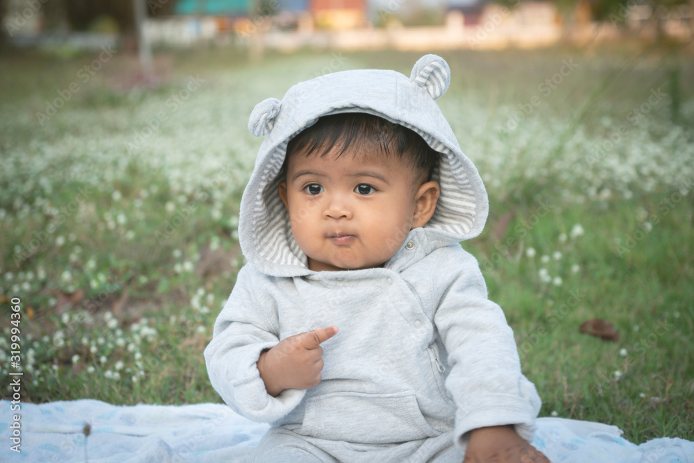 Cute little asina baby sitting at white flower garden Cute little asina baby sitting at white flower garden