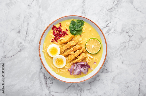 Ohn No Khao Swe on white marble background. Oh No Khao Suey is Coconut Milk Noodle Soup of myanmar cuisine with chicken meat and eggs. Burmese food. Top view. Copy space photo