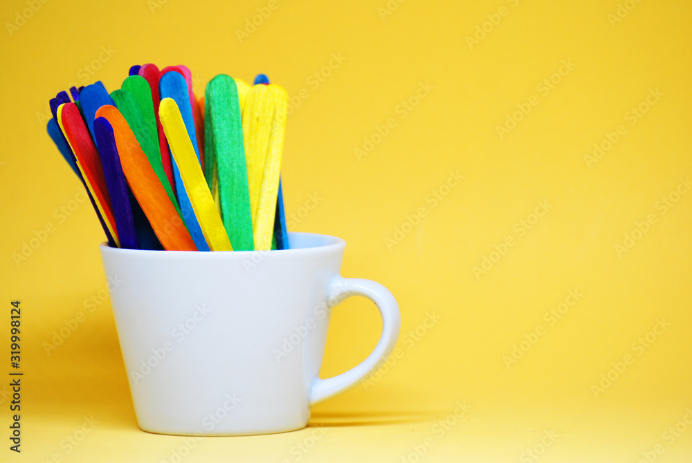 Colorful Ice cream stick on the white cup isolated with yellow pastel background -  Decorate Back to school concept with copy space