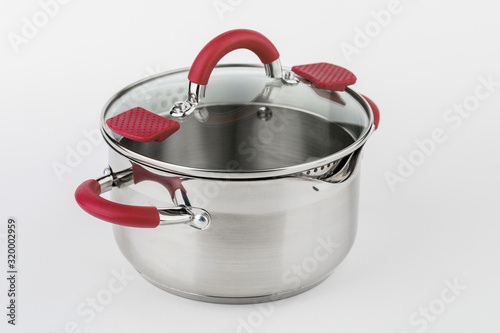 Stainless casserole with glass lid and red handles on grey background. photo