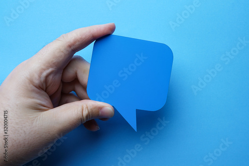 Man holding blank blue speech bubble on blue background.