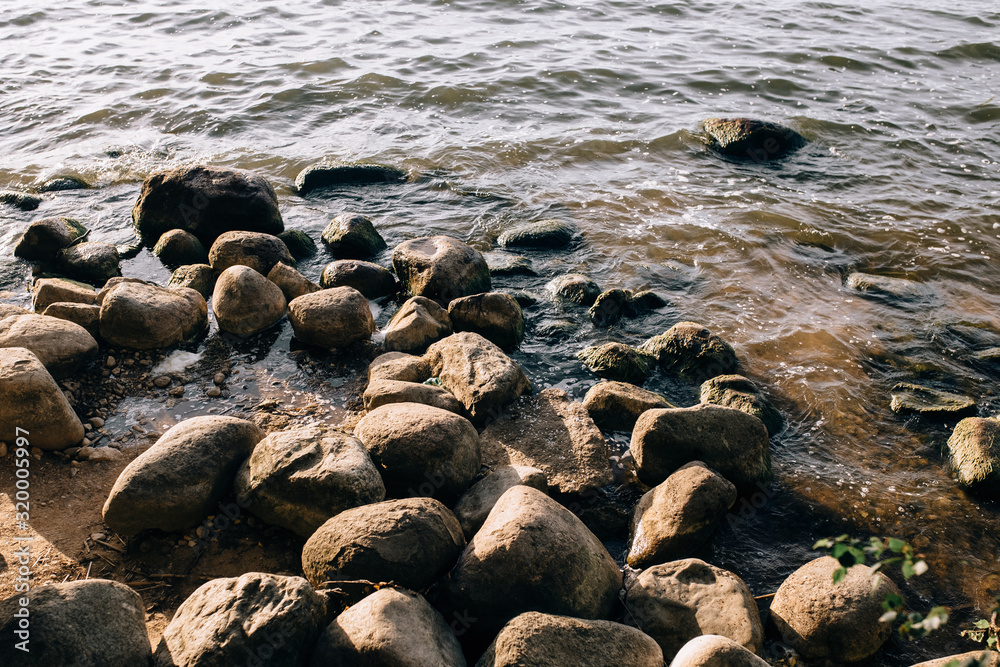 Obraz premium Stones on the lake in the fog. Big and small stones. The water is transparent and under the water you can see stones overgrown with silt. Copy space.