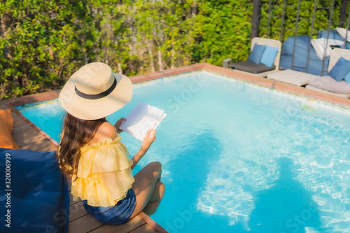 Portrait young asian woman read book around outdoor swimming pool