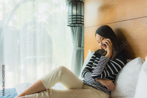Portrait young asian woman using smart mobile phone on bed in bedroom