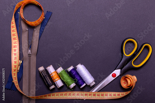 Copyspace frame with sewing tools and accesories. Tools for sewing and handmade: thread, scissors, pins on black paper.